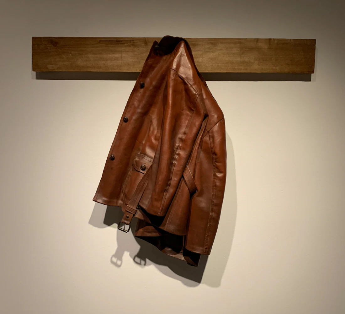 Brown leather jacket hanging on a wooden hook